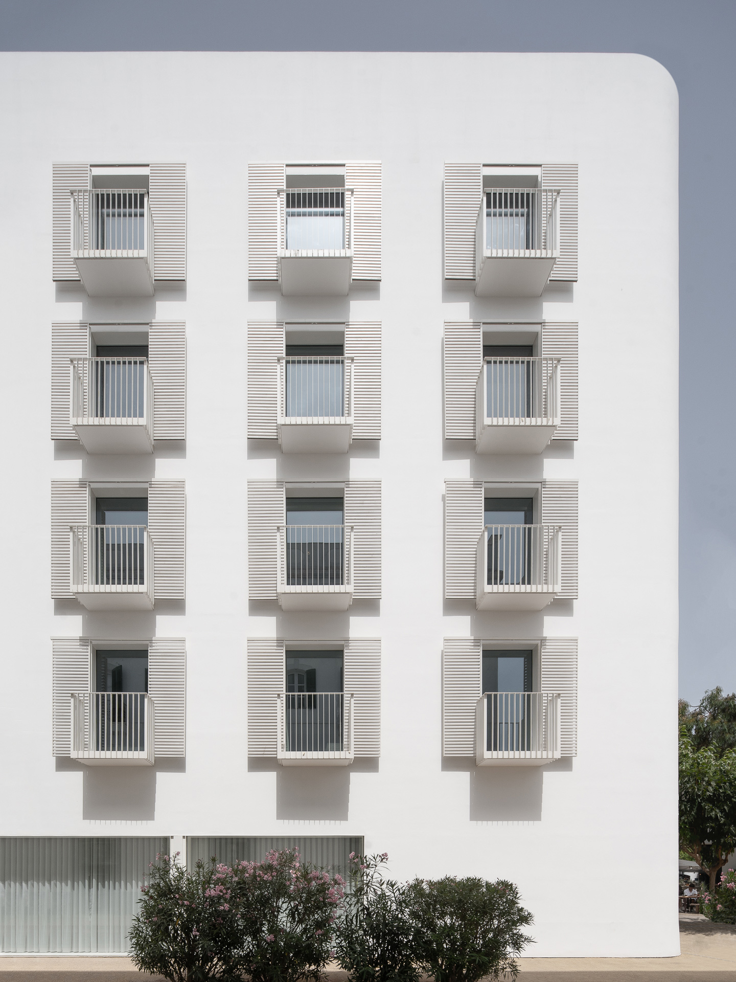 Weißes Gebäude mit 12 Terrassentüren und kleinen Balkonen